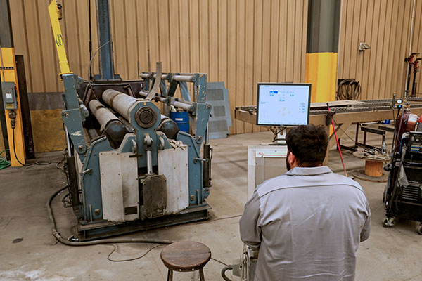 Worker operating CNC 4 roll plate roller