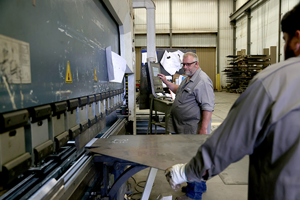 Workers operating CNC Press Brake