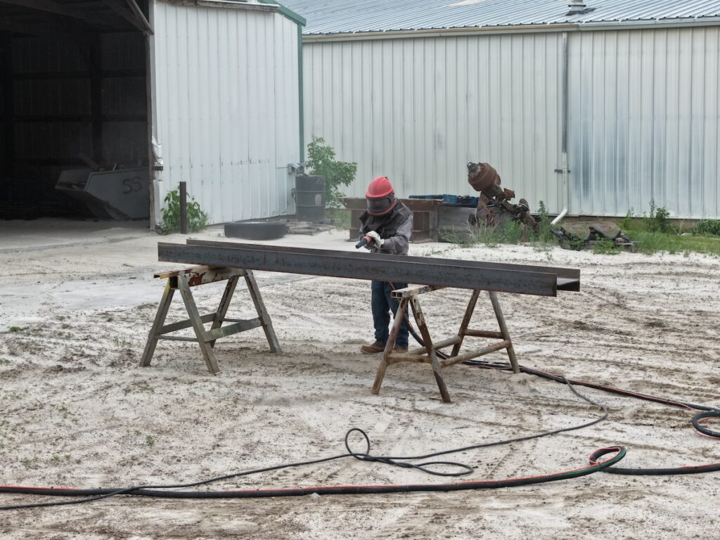 Worker sand blasting material in outdoor area