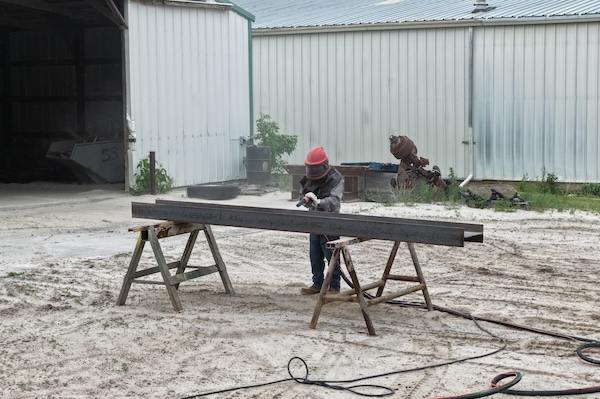 Worker sand blasting in outdoor area